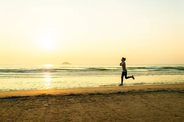 Woman running on beach at sunrise