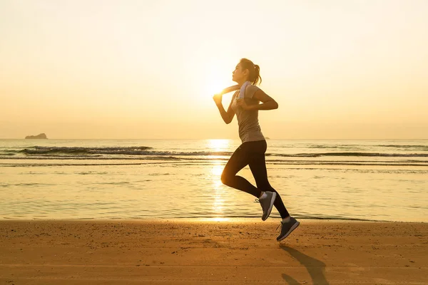 Woman running on beach at sunrise — Stock Photo, Image