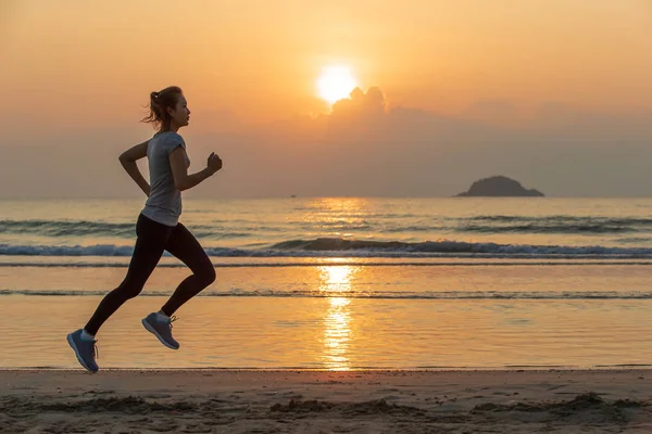 Woman running on beach at sunrise — Stock Photo, Image