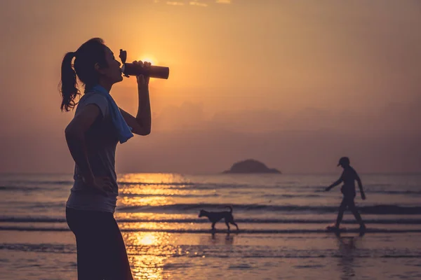 在海滩喝水的女人 — 图库照片