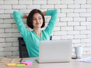 Genç ve tatlı yarı yarış Taylandlı Alman kadın çalışma masasında oturuyor ve evde uzun bir iş sırasında tembellikten kurtulmak için ellerini başının üstüne koyuyor. Ev fikri üzerinde çalış..