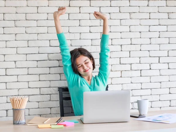 Genç ve tatlı yarı yarış Taylandlı Alman kadın çalışma masasında oturuyor ve evde uzun bir iş sırasında tembellikten kurtulmak için ellerini başının üstüne koyuyor. Ev fikri üzerinde çalış..