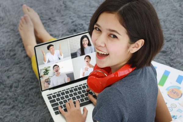 Businesswoman in casual dress sitting on floor with open smile face in living room, using laptop notebook computer to meeting distance talk with four friends. They are happy and laugh with funny.