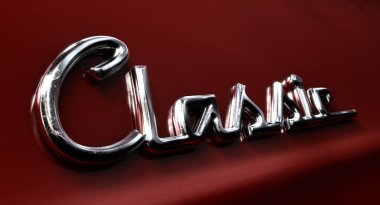 Klasik kelimesinin, yansıtıcı kırmızı boya ile boyanmış bir arabanın retro font setinde krom amblem olarak yazılmış yakın plan görüntüsü - 3D