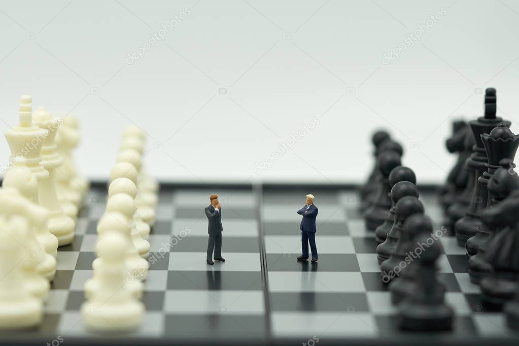 Miniature 2 people businessmen standing on a chessboard with a chess piece on the back Negotiating in business. as background business concept and strategy concept with copy space.