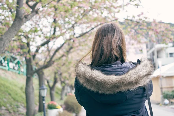 Asian women, white skin aged 25-30 years holding a smart phone, photographed cherry blossoms (sakura flower) beside the river. Feels fresh and beautiful. Spread the cold air. In Japan