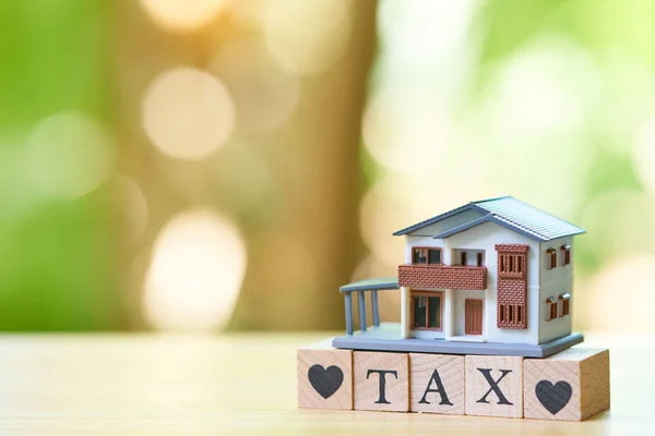 A model house model is placed on wood word TAX . as background property real estate concept with copy space for your text or  design.