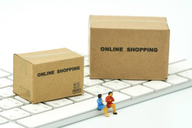 Minyatür iki kişi Online beyaz klavye üzerinde oturan bir alışveriş sepeti ve alışveriş torbaları gibi arka plan alışveriş kavramı ve teslimat hizmeti kavramı kopya alanı ile teslim hizmeti kullanma ile alışveriş