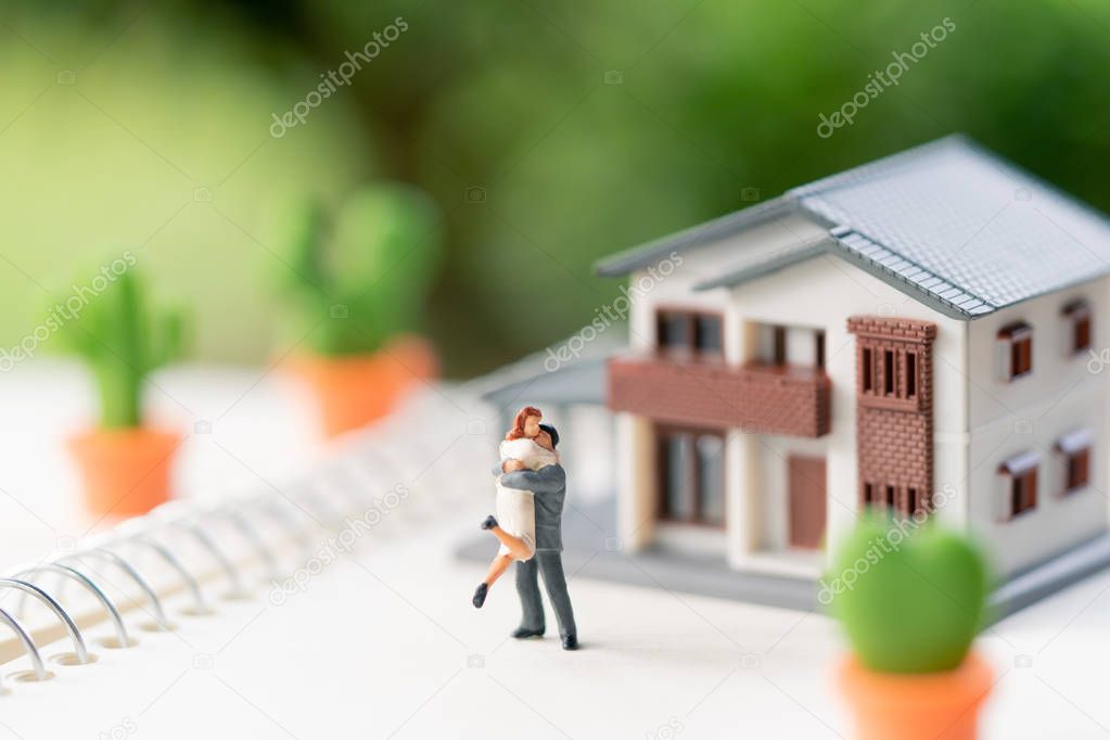 Couple Miniature 2 people standing model with house model make family Feel happy.as background real estate and family concept with copy space.