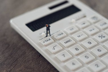 Minyatür insan Pay sıra yıllık gelir (vergi) hesap makinesi üzerinde yıl için. arka plan iş kavramı ve ekonomi kavramı kopya alanı ile metin veya tasarım için kullanma.