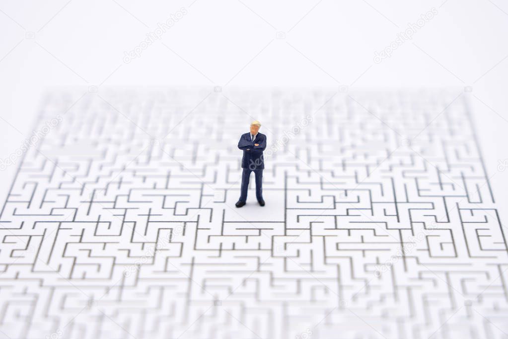Miniature people businessmen standing in the center of the maze.