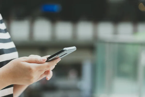 Eine schöne asiatische Frau benutzt ein Smartphone in der Innenstadt, um — Stockfoto