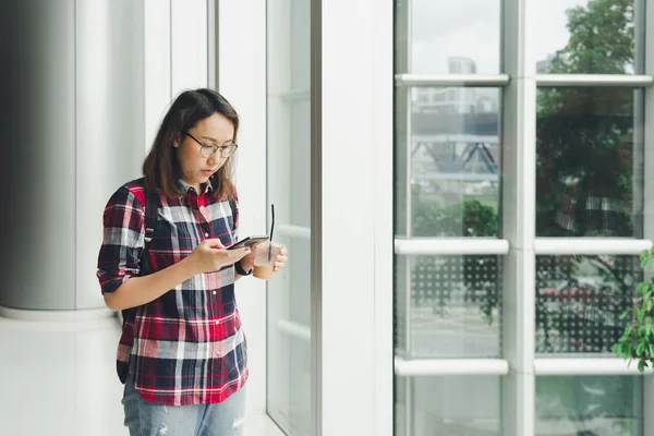 Eine schöne asiatische Frau benutzt ein Smartphone in der Innenstadt, um — Stockfoto