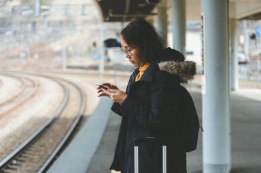 Güzel Asyalı bir kadın için şehir merkezinde bir akıllı telefon kullanır 