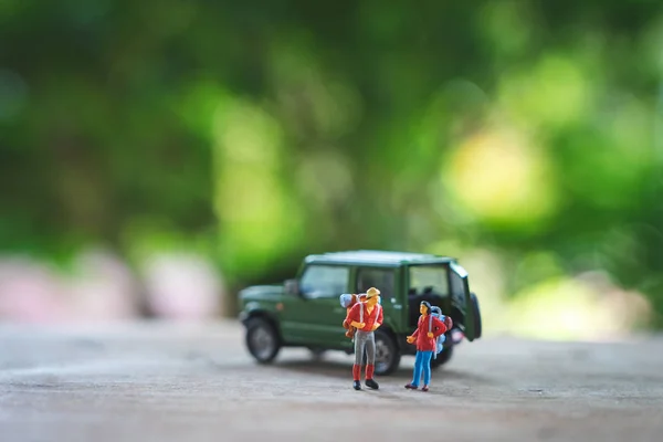 Miniatur 2 Personen stehend Reiseplaner mit gelbem Spielzeugauto m — Stockfoto