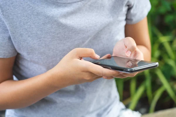 Asiatische Mädchen spielen Smartphone zur Unterhaltung und arbeiten draußen — Stockfoto