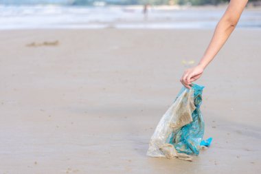 Kumsalda kullanılmış plastik poşet taşıyan bir kadın, Cleani.