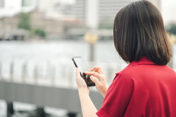 Eine schöne asiatische Frau benutzt ein Smartphone in der Innenstadt, um — Stockfoto