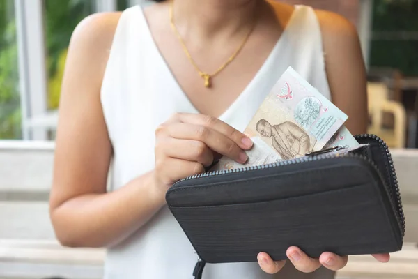 Asian women pick up Thai banknotes from the purse to pay for foo