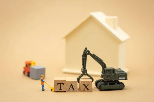 Personas en miniatura Trabajador de la construcción de pie con palabra de madera TAX — Foto de Stock