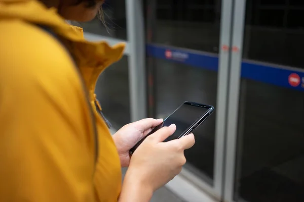 Eine schöne asiatische Frau benutzt ein Smartphone in der Innenstadt, um — Stockfoto