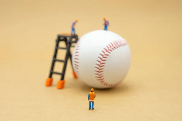 Miniature people Construction worker with baseball on Abstract b