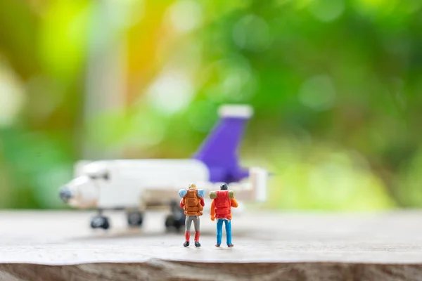 Miniature 2 people standing travel planner with Plane model as b