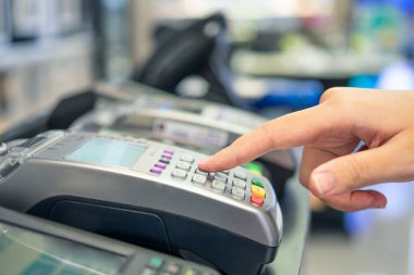 Kredi kartı kaydırma makinesi ve elinde kredi arabası olan genç bir kadın.