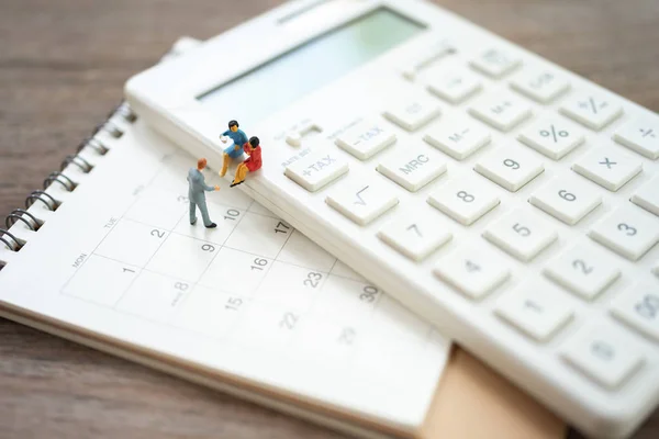 Miniature people sitting on white calculator using as background — Stock Photo, Image