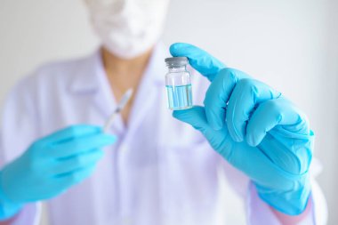 Steteskoplu kadın doktor ya da bilim adamı şırınga ve COVID-19 ya da koronavirüs aşısı taşıyor. Sağlık ve Tıp Konsepti.