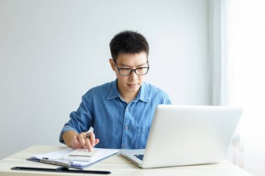 Evde çalışan genç Freelancer ya da iş adamı akıllı telefon tabletiyle çalışıyor. Çevrimiçi çalışmak ya da çalışırken öğrenmek. Ev kavramından Serbest Çalışma, İş ve Çalışma