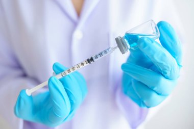 Steteskoplu kadın doktor ya da bilim adamı şırınga ve COVID-19 ya da koronavirüs aşısı taşıyor. Sağlık ve Tıp Konsepti.