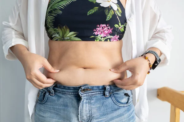 Women body fat belly. Obese woman hand holding excessive belly fat. diet lifestyle concept to reduce belly and shape up healthy stomach muscle.