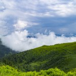 Bavarian Alps with blue sky with clouds. Green grass fields on rainy day