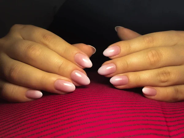 Cuidado con las uñas. Manos de mujer con manicura en un fondo de tela rosa — Foto de Stock