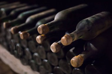 Enoteca. Şarap mahzeninde şarap koleksiyonu. Raftaki şişeler yakın çekimde