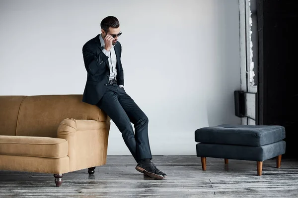 Young stylish businessman leader indoors at office in sunglasses walking looking aside