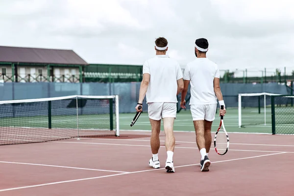 Never give up-Two tennis players leaving the tennis court