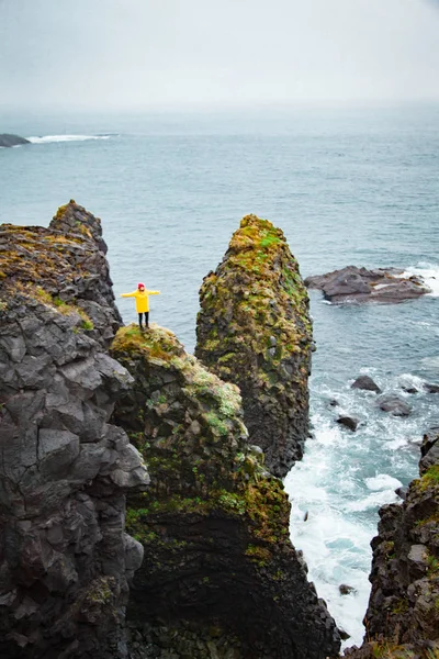 Icelandic landscape, person in yellow rain jacket. Amasing rock, Iceland.