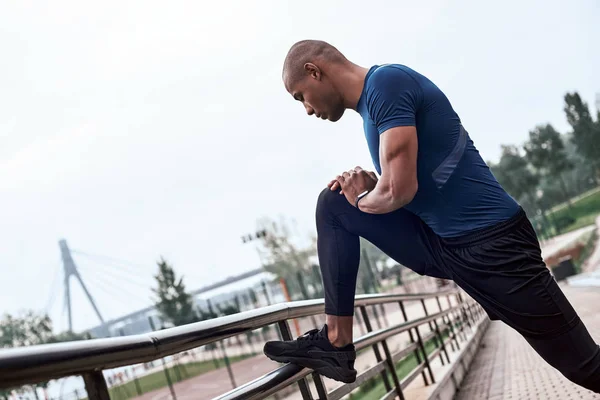 Side view portrait of an african sportive man who is stretching legs