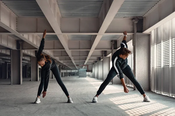 Young man and woman are doing warming up exercises at parking