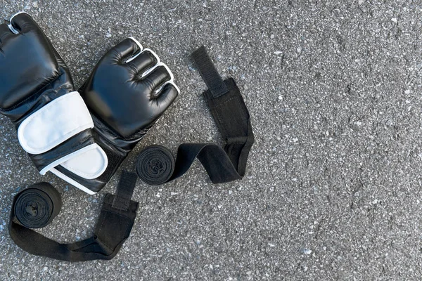 Sports boxing gloves with boxing bandages at the asphalt background