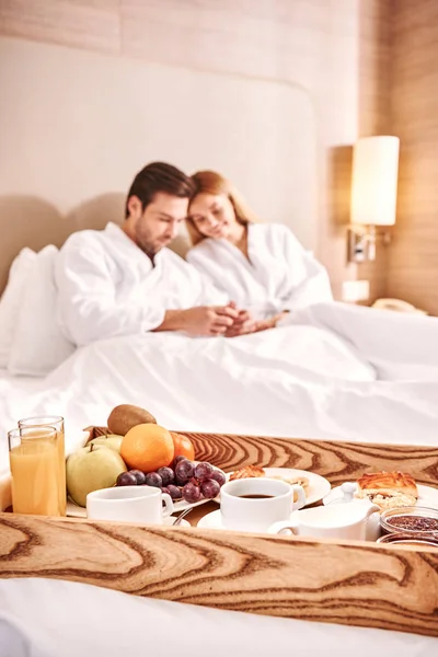 Breakfast in hotel room. Couple are hugging in hotel room bed