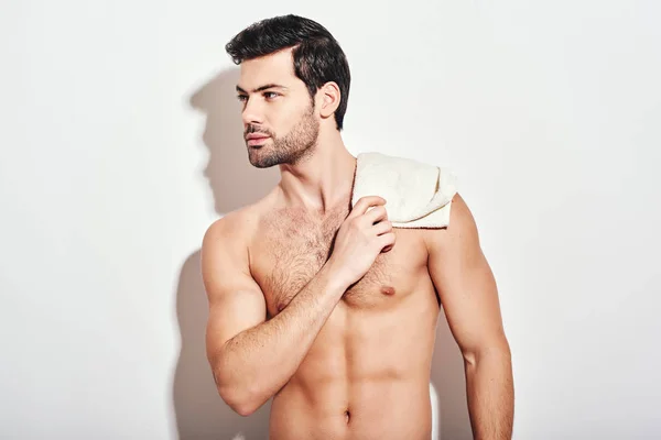 Its bathtime Handsome man standing shirtless holding white towel isolated over white background