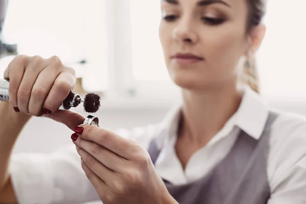 Creating a beauty. Close-up portrait of young female jeweler preparing polishing tool for making jewelry.