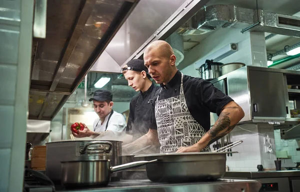 Concentrated at work. Professional team of chef and two young assistants cooking in a restaurant kitchen