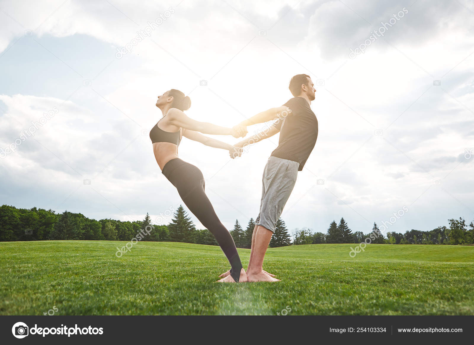 Yoga in pair. Beautiful young couple practicing acro yoga together and stretching in nature on a sunny morning. Healthy lifestyle. Various yoga poses Yoga in pair. Beautiful young couple practicing acro yoga together and stretching in nature on a sunny morning. Healthy lifestyle. Various yoga poses