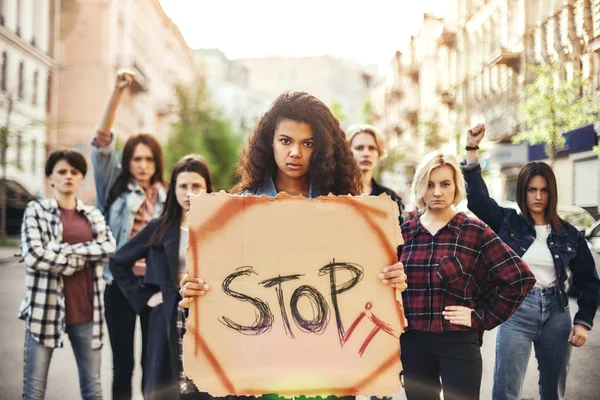 Stop War Make Peace. Young woman is holding a banner with word stop it while standing on the road during a womens march in front of female activists