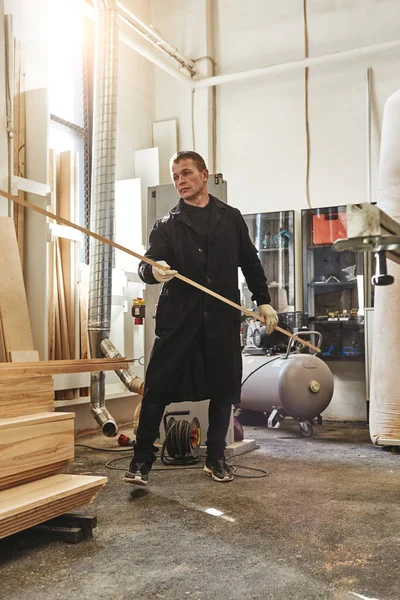 Carpenter working in wood factory. Vertical shot