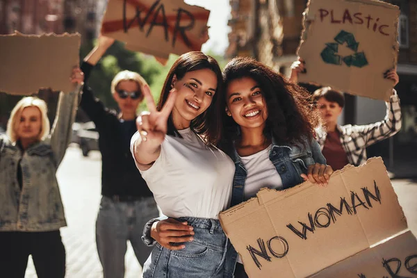 The power of woman Two young and happy activists holding a banner with slogan while standing on the road in front of female demonstrators